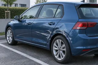Parkendes Auto mit Lackabschürfung und flacher Delle an Tür und Radlauf